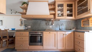 A modern kitchen with wooden cabinets, a built-in oven, and a marble backsplash.