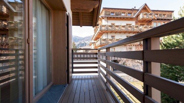 A wooden balcony with a view of a mountain and traditional buildings.