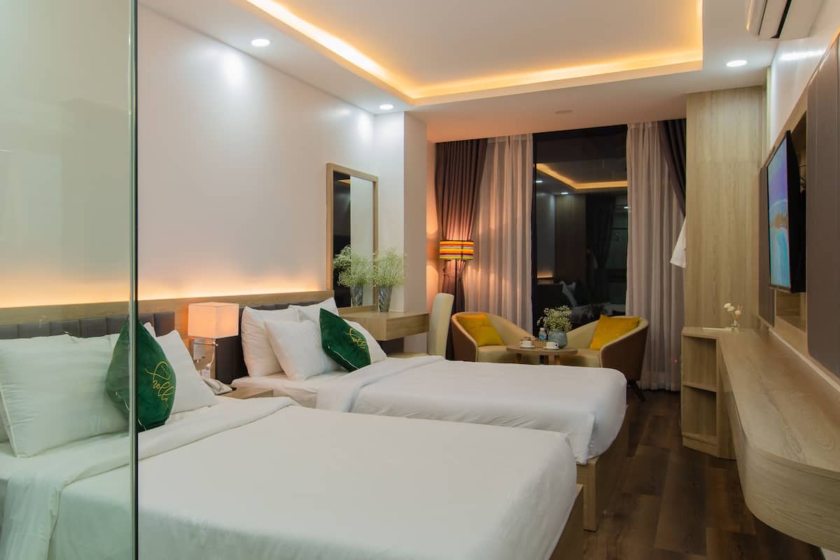 Une chambre d’hôtel avec deux lits, un bureau, une chaise, une télévision et un miroir.