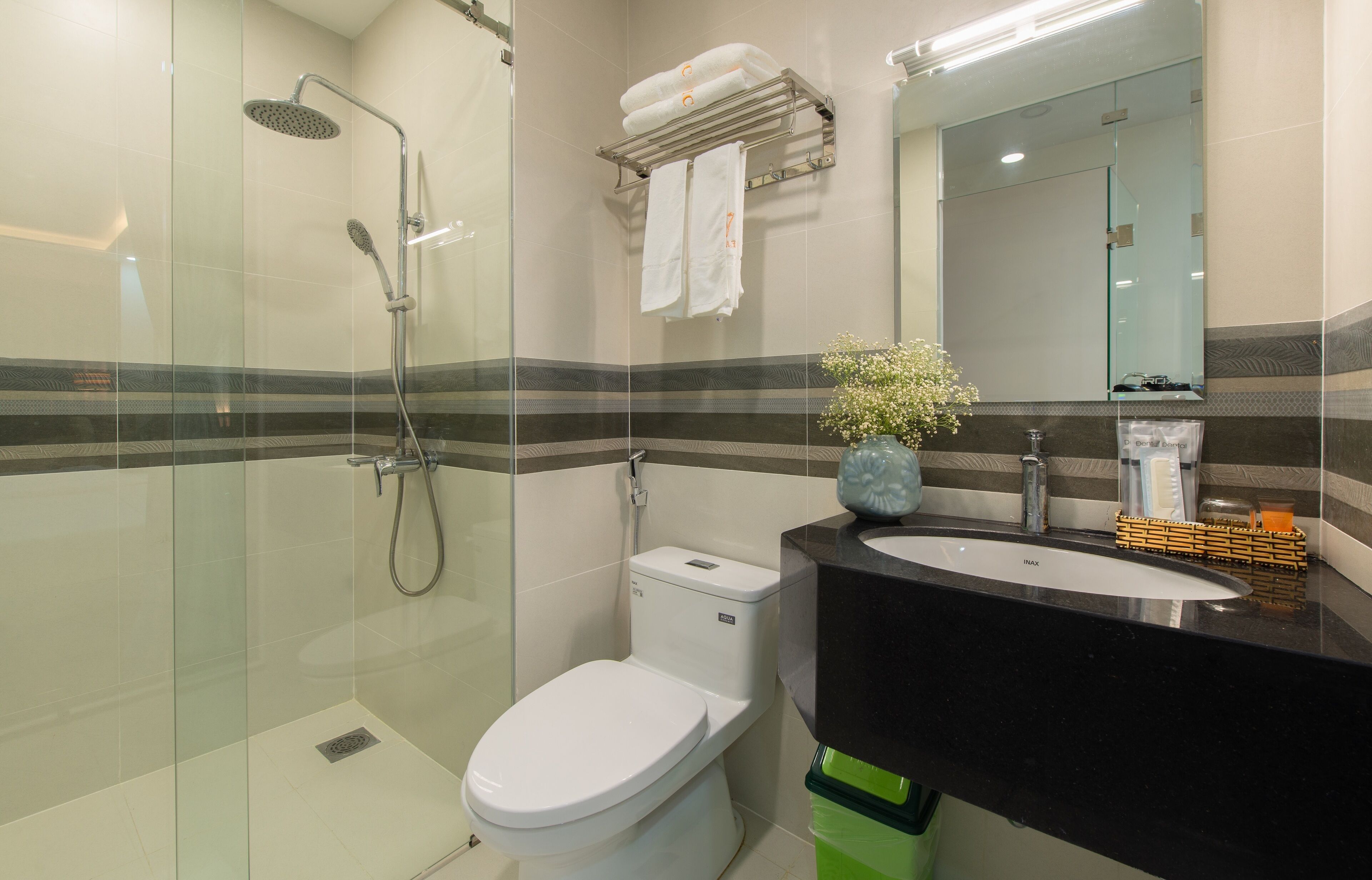 A modern bathroom with a glass-enclosed shower, a white toilet, a black sink, and a mirror above the sink.