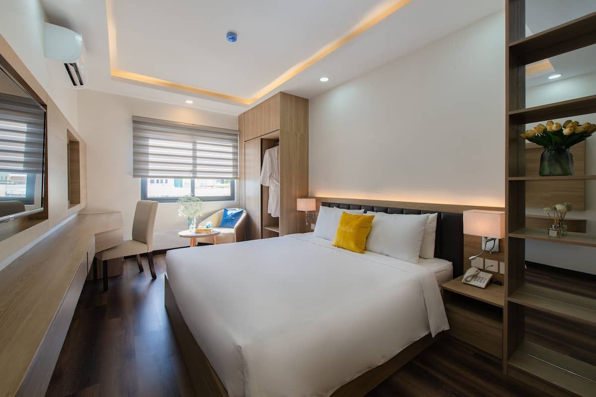 Une chambre d’hôtel avec un grand lit, une table de chevet, une lampe et un petit coin salon comprenant une chaise et une table.