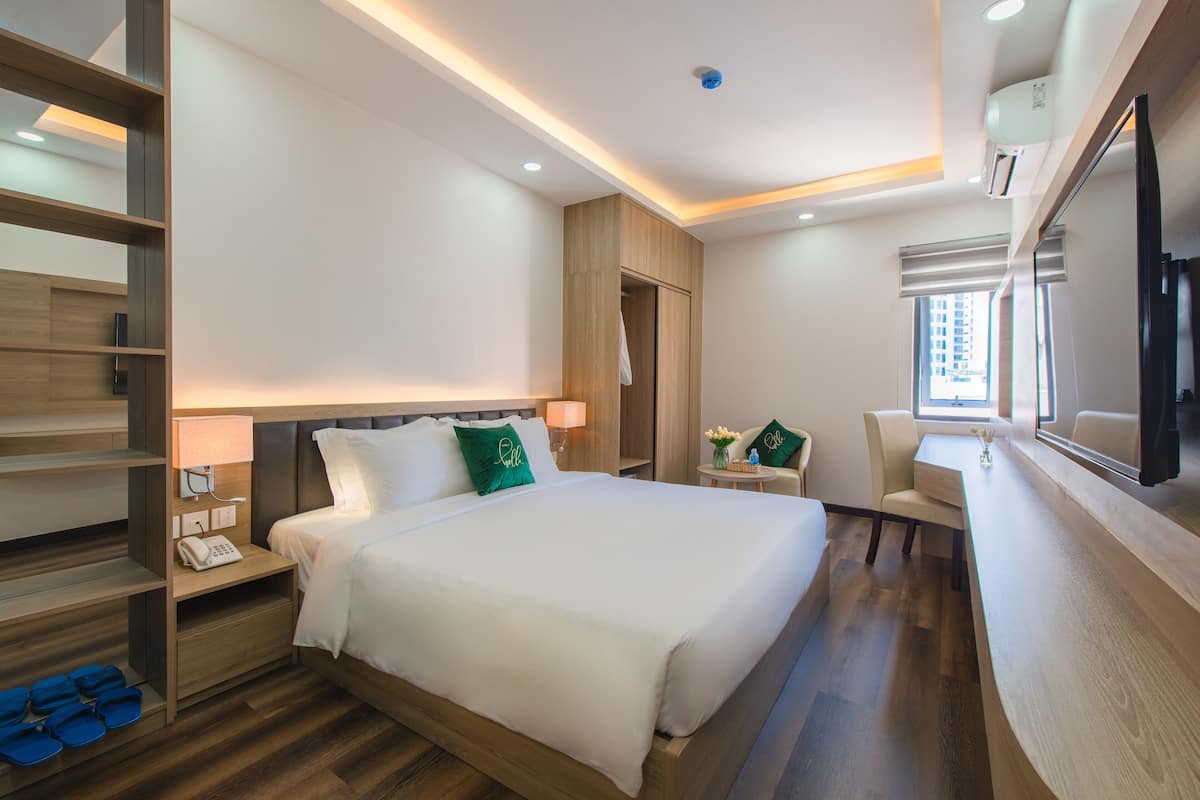 Une chambre d’hôtel comprenant un lit, une table de chevet, une lampe et une petite table avec une chaise.