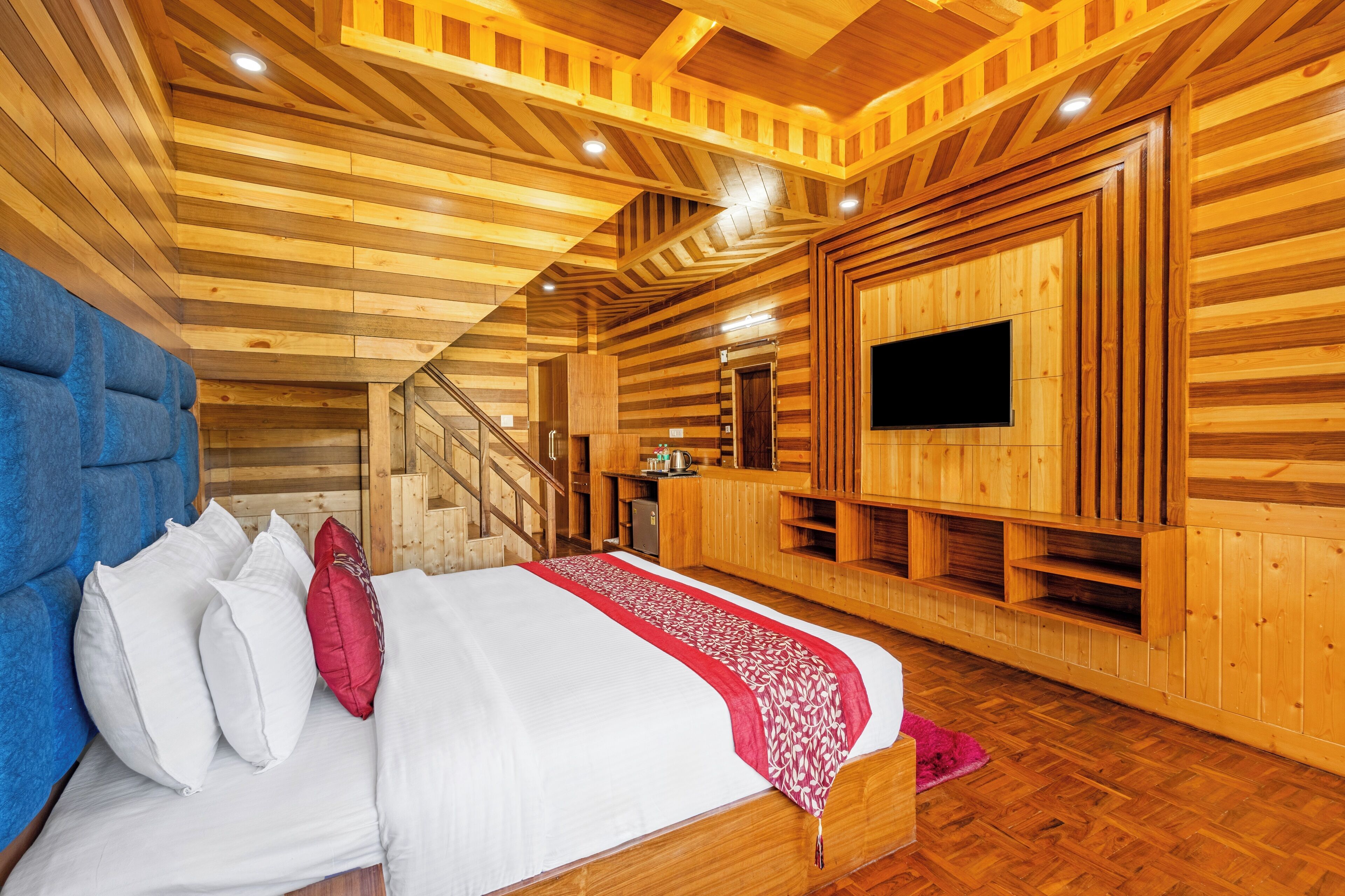 Une chambre à coucher de style cabane en bois, avec un lit, des oreillers, un téléviseur et un escalier.