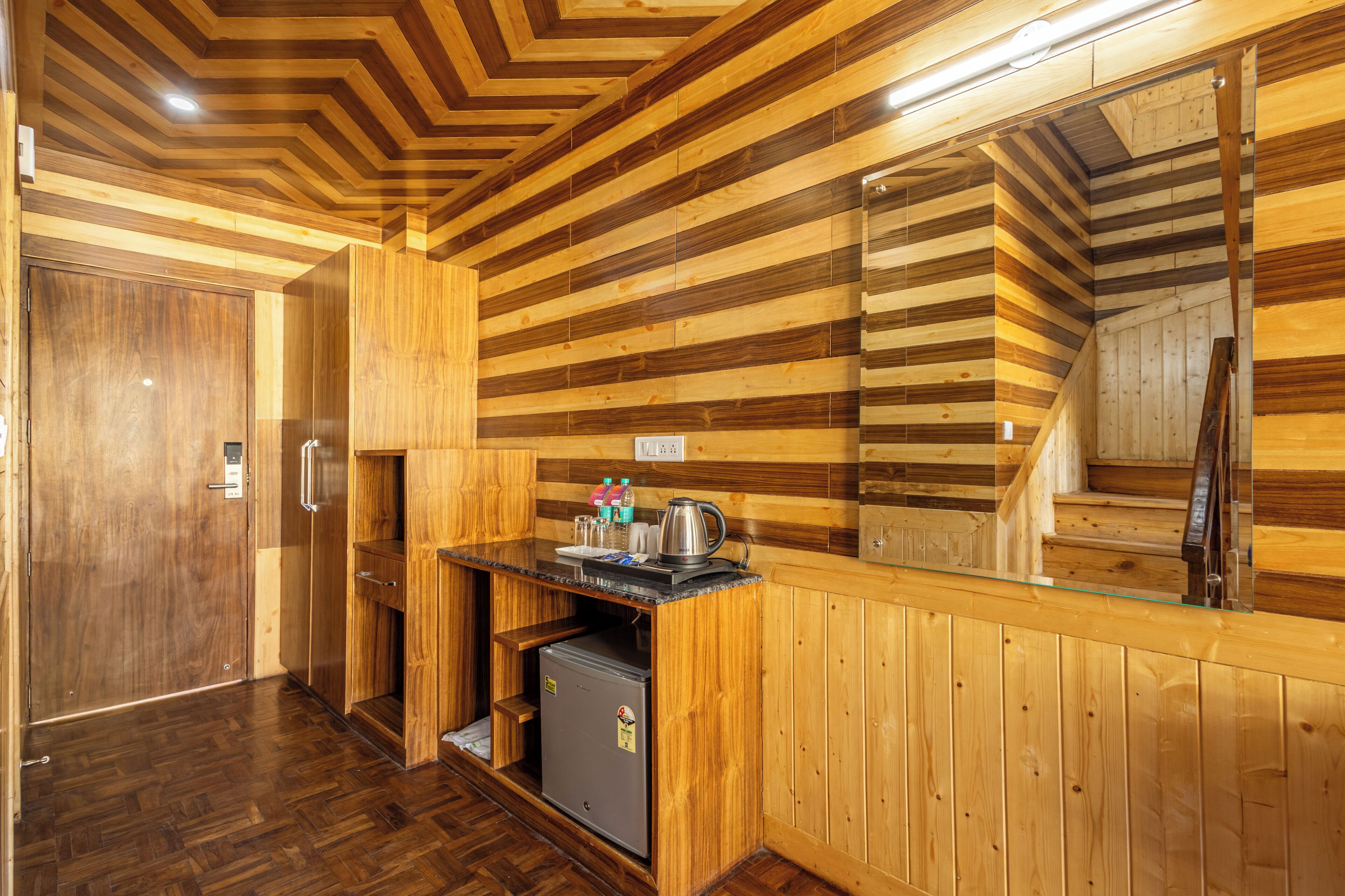 A wooden interior with a kitchenette, a refrigerator, and a wooden door.