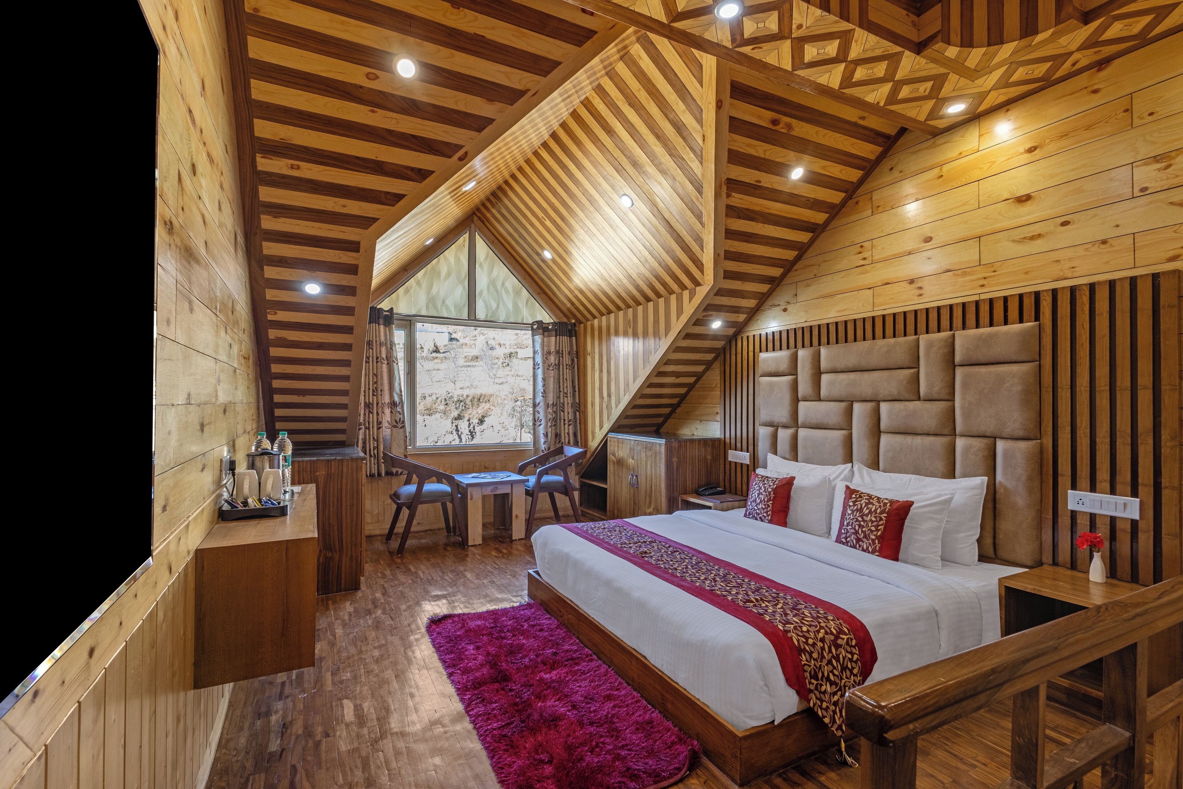 Camera da letto in una baita di legno, con un letto grande, una scrivania e una sedia.