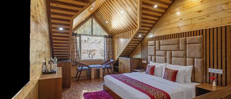 Camera da letto in una baita di legno, con un letto grande, una scrivania e una sedia.