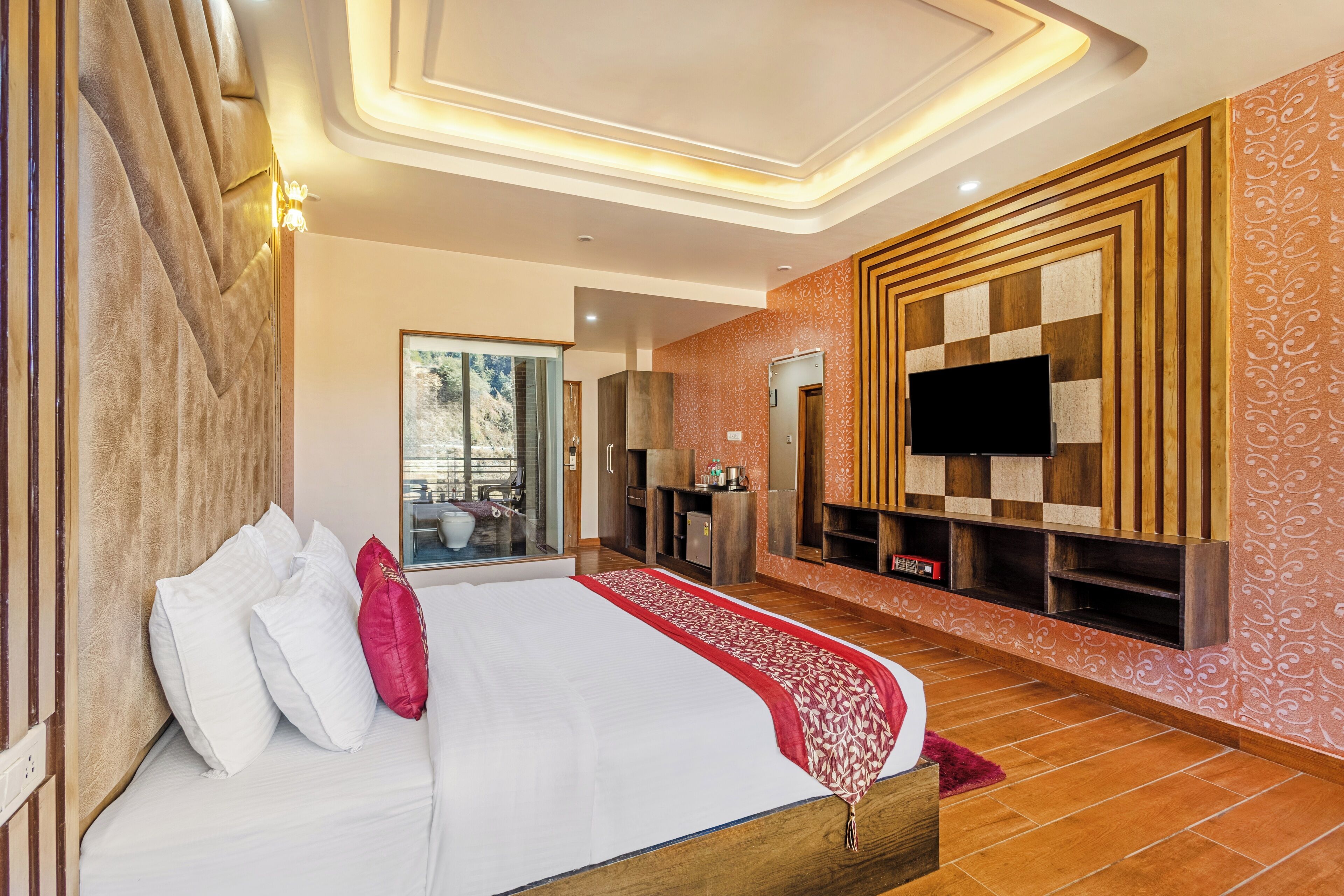 A modern hotel room with a large bed, a TV mounted on the wall, and a balcony with a view.