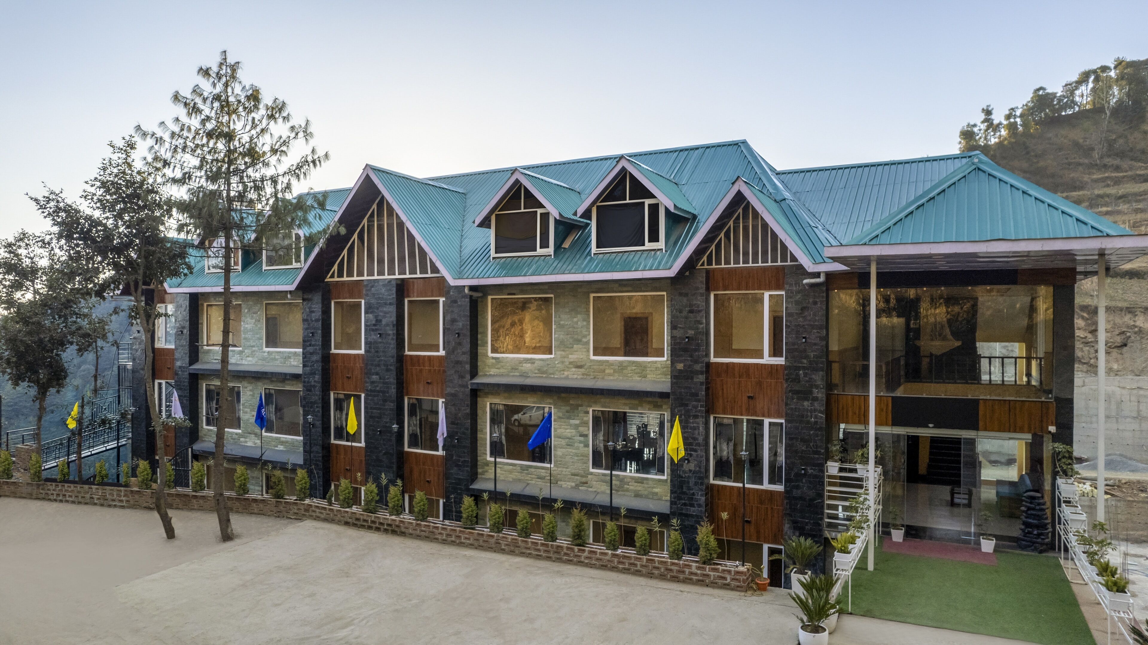 A multi-story hotel with a modern architectural design, featuring a mix of stone and wood exterior materials, large windows, and a green roof.