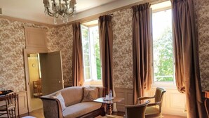 Een hotelkamer met een bed, een bank, een stoel, een klein tafeltje en een kroonluchter.
