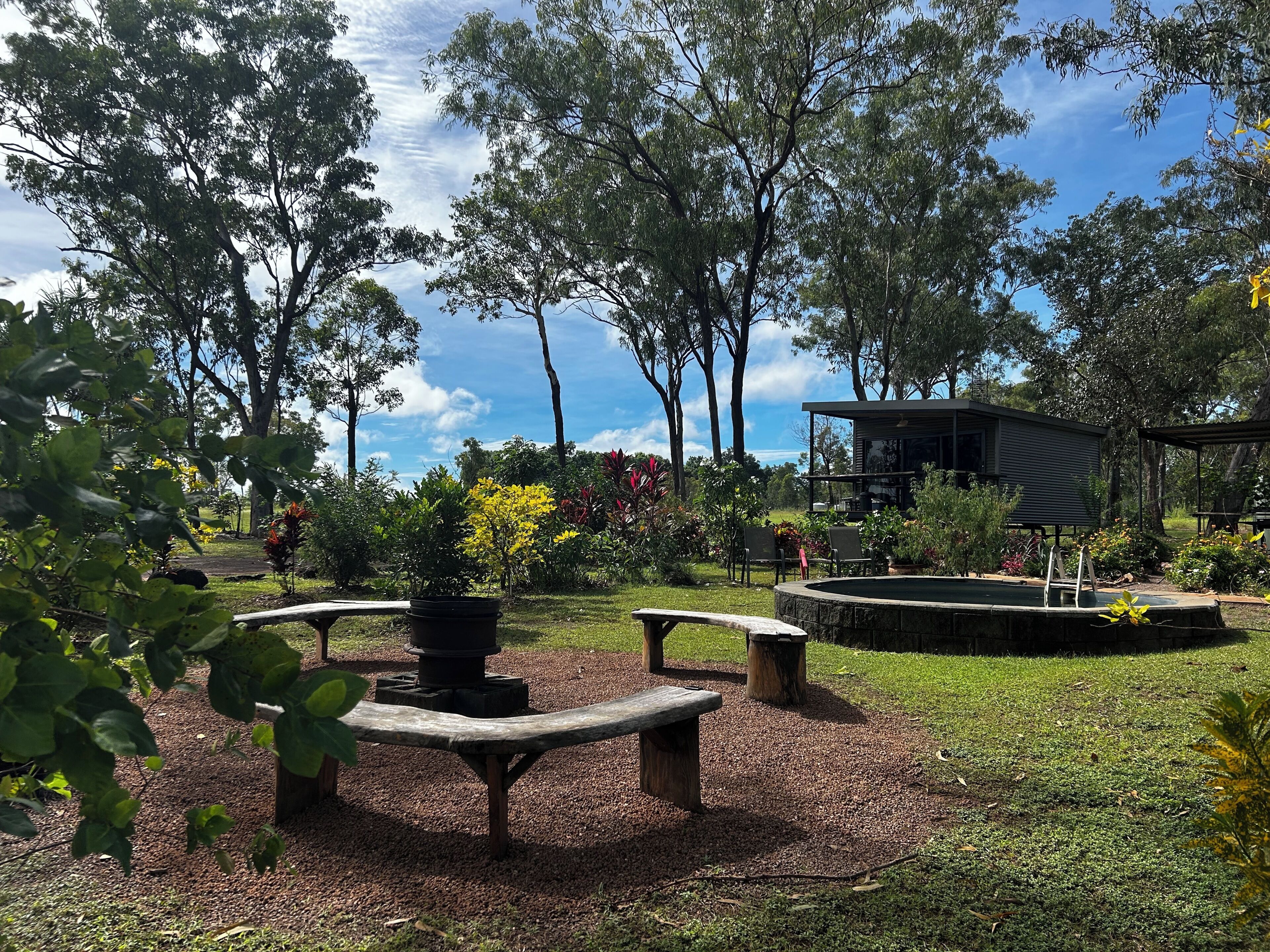 Un jardin doté d’un espace de repos circulaire, d’une petite piscine et d’un bâtiment avec un patio couvert.