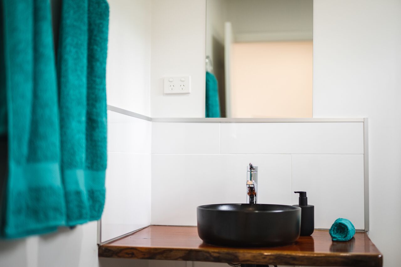 Une salle de bain avec un lavabo noir, un miroir et une serviette turquoise accrochée au mur.