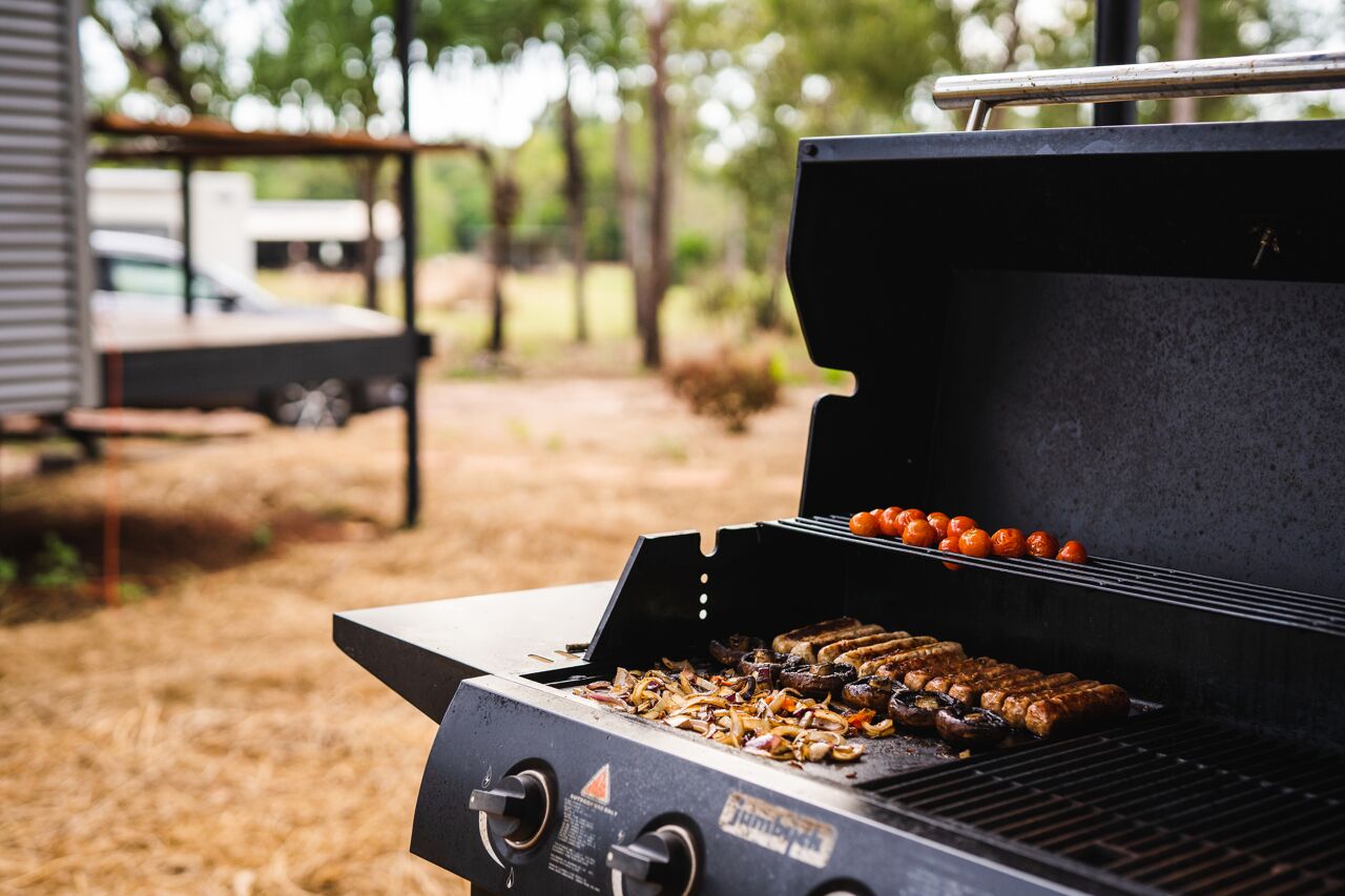 Un barbecue portable sur lequel on fait griller des saucisses et des légumes.
