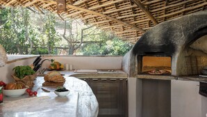 An outdoor kitchen with a pizza oven, a cutting board, and various fresh ingredients. - Villa Padulella 8 2 Emma Villas (Portoferraio)