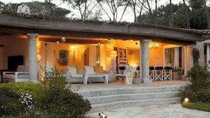 A covered outdoor seating area with stone columns, a sofa, and a dining table. - Villa Padulella 8 2 Emma Villas (Portoferraio)