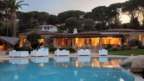 A poolside area with outdoor seating and a stone building in the background.