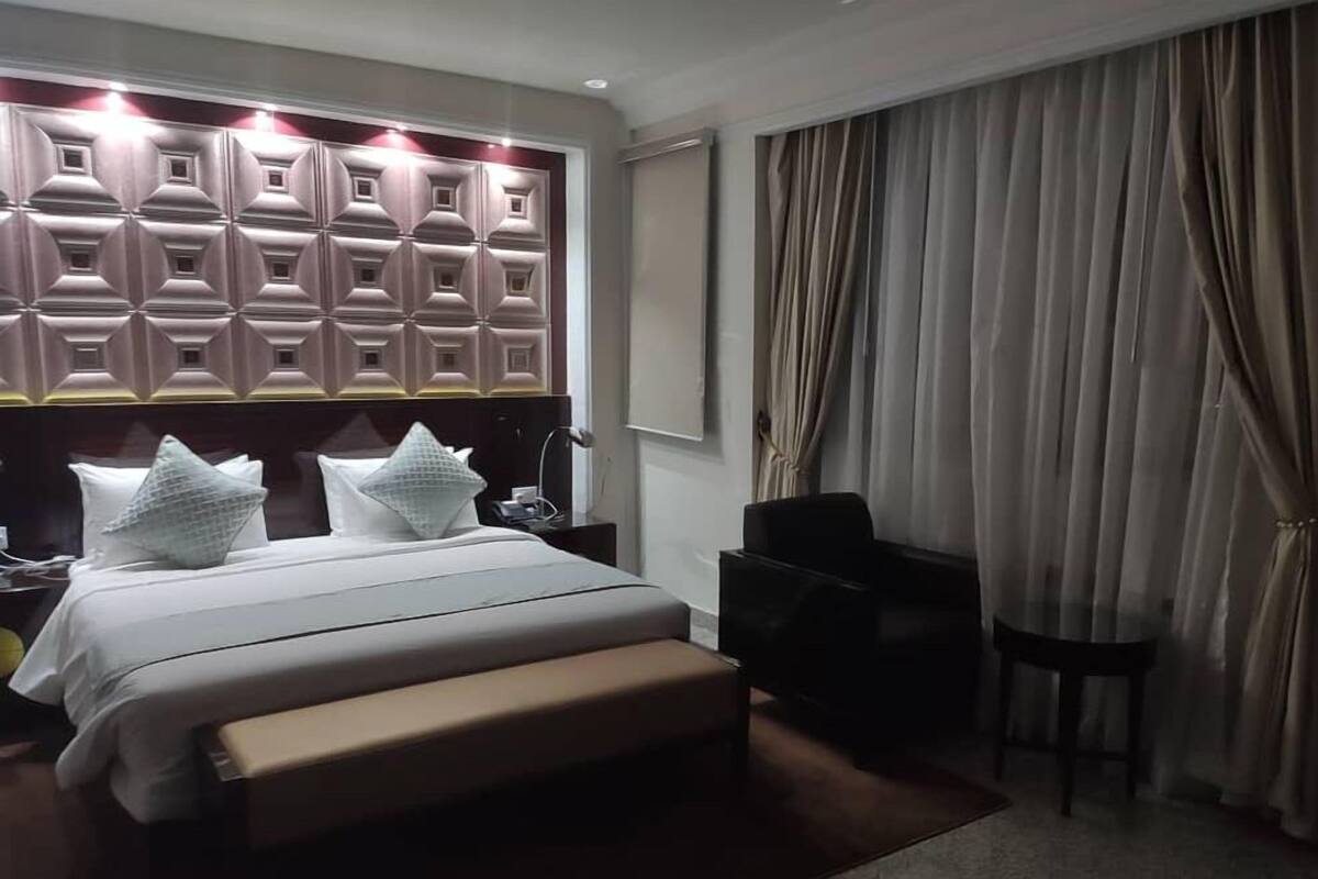 Una habitación de hotel con una cama grande, un cabecero de estampado geométrico, una mesita de noche, una silla y un escritorio.