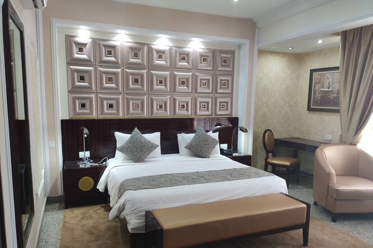 Una habitación de hotel con una cama grande, mesitas de noche, un escritorio y una silla.