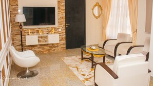 A modern living room with a TV, two sofas, a coffee table, and a decorative mirror. - Conference Hotel (Abeokuta)