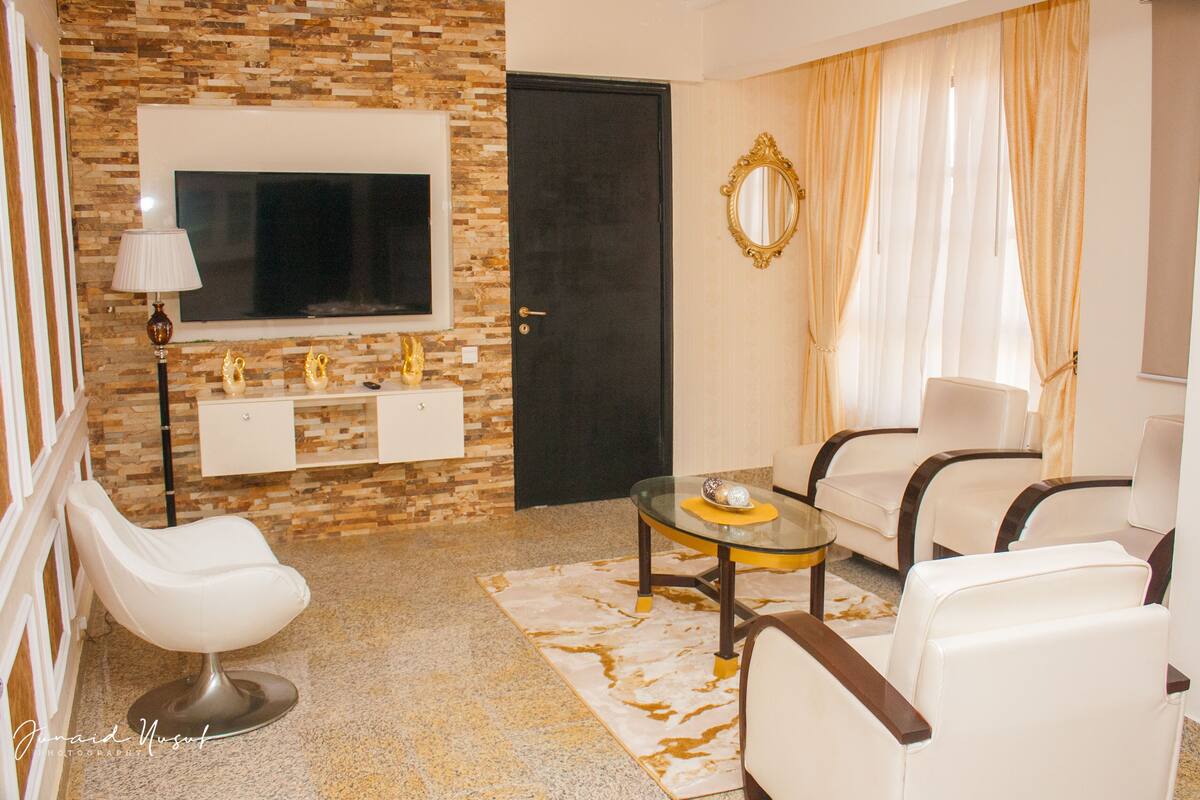 Una sala de estar moderna con un televisor, dos sofás, una mesa de centro y un espejo decorativo.