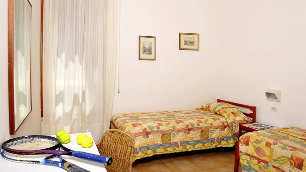 Un dormitorio con dos camas, un espejo, una ventana con cortinas y una lámpara en la pared.