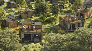 Una zona residencial moderna y ecológica con estructuras de madera, mobiliario exterior y un sendero central.