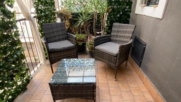 A small patio area with wicker furniture, a glass table, and potted plants. - Luxury Suite Center (Catania)
