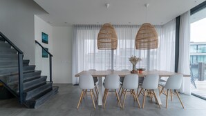 A modern dining area with a wooden table and six chairs, a staircase with black railings, and large windows with sheer curtains. - Waterfront holiday home in Arnemuiden (Arnemuiden)