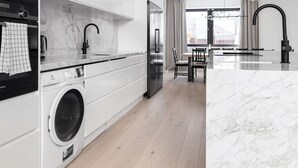 Una cocina moderna con lavadora incorporada, un comedor y un amplio ventanal.