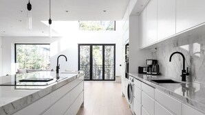 Una cocina moderna con encimeras de mármol, grifos negros y una isla grande.
