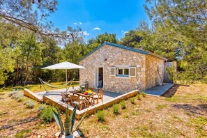 Une maison en pierre avec un patio, du mobilier d’extérieur et un hamac.