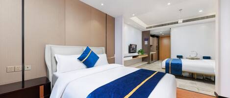 A hotel room with a large bed, a smaller bed, a desk, and a bathroom visible through an open door.