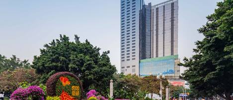 A landscaped garden with colorful flowers and a tall building in the background.