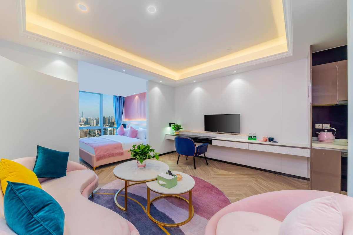 Quarto de hotel moderno com cama, escrivaninha, televisão e vista para a cidade.
