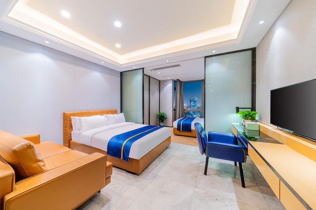 Quarto de hotel moderno com uma cama grande, uma escrivaninha, uma cadeira e uma televisão.