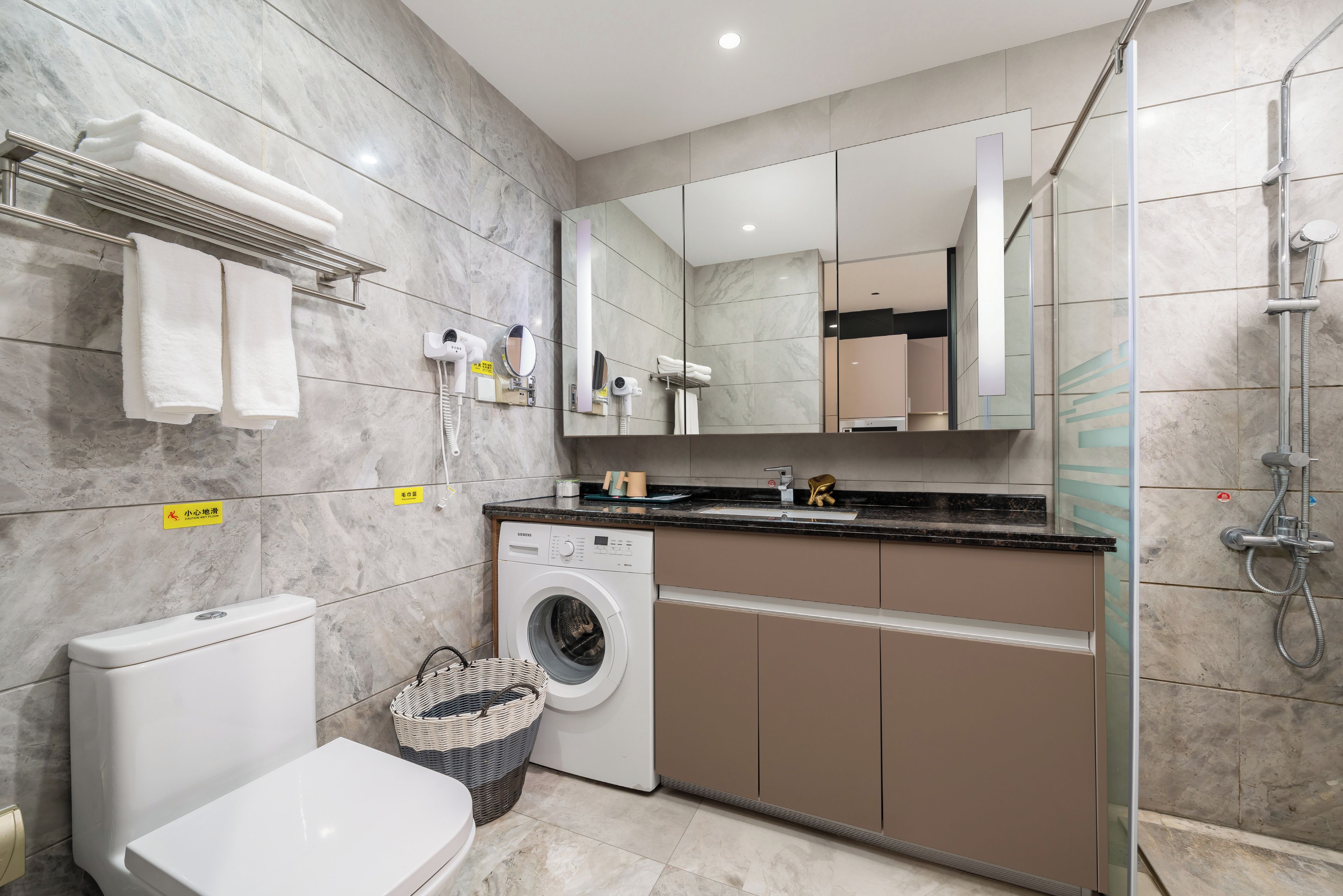 A modern bathroom with a toilet, washing machine, and shower area.