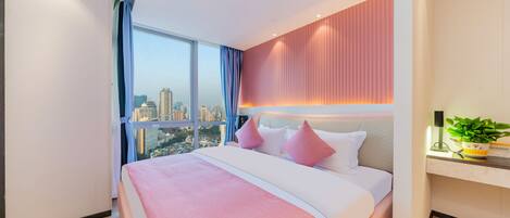 A modern hotel room with a large bed, a desk, and a city view.