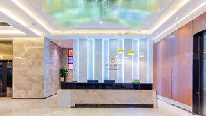 A hotel reception area with a marble reception desk, vertical light fixtures, and a green decorative hanging. - Cloudy International Apartment (Guangzhou)