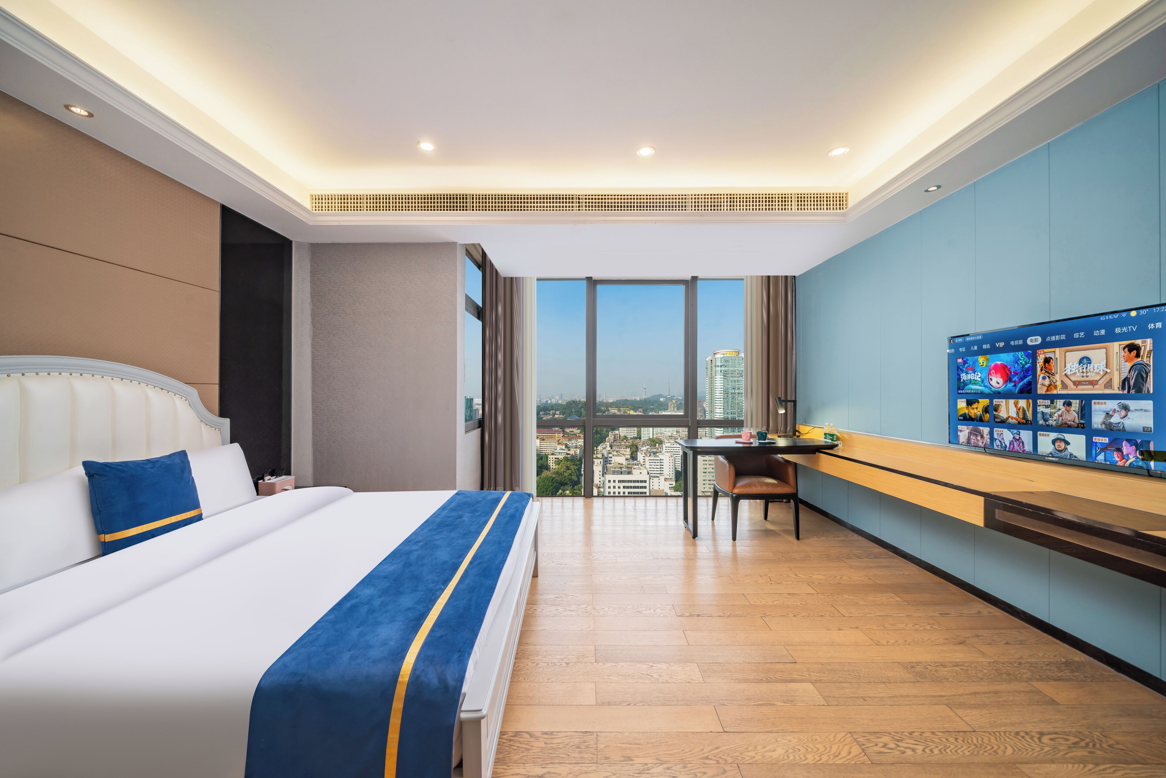A hotel room with a large bed, a desk, and a view of the city.