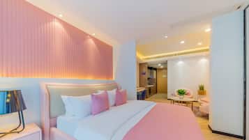 Una habitación de hotel moderna con una cama grande, una mesita de noche y una pequeña zona de escritorio.