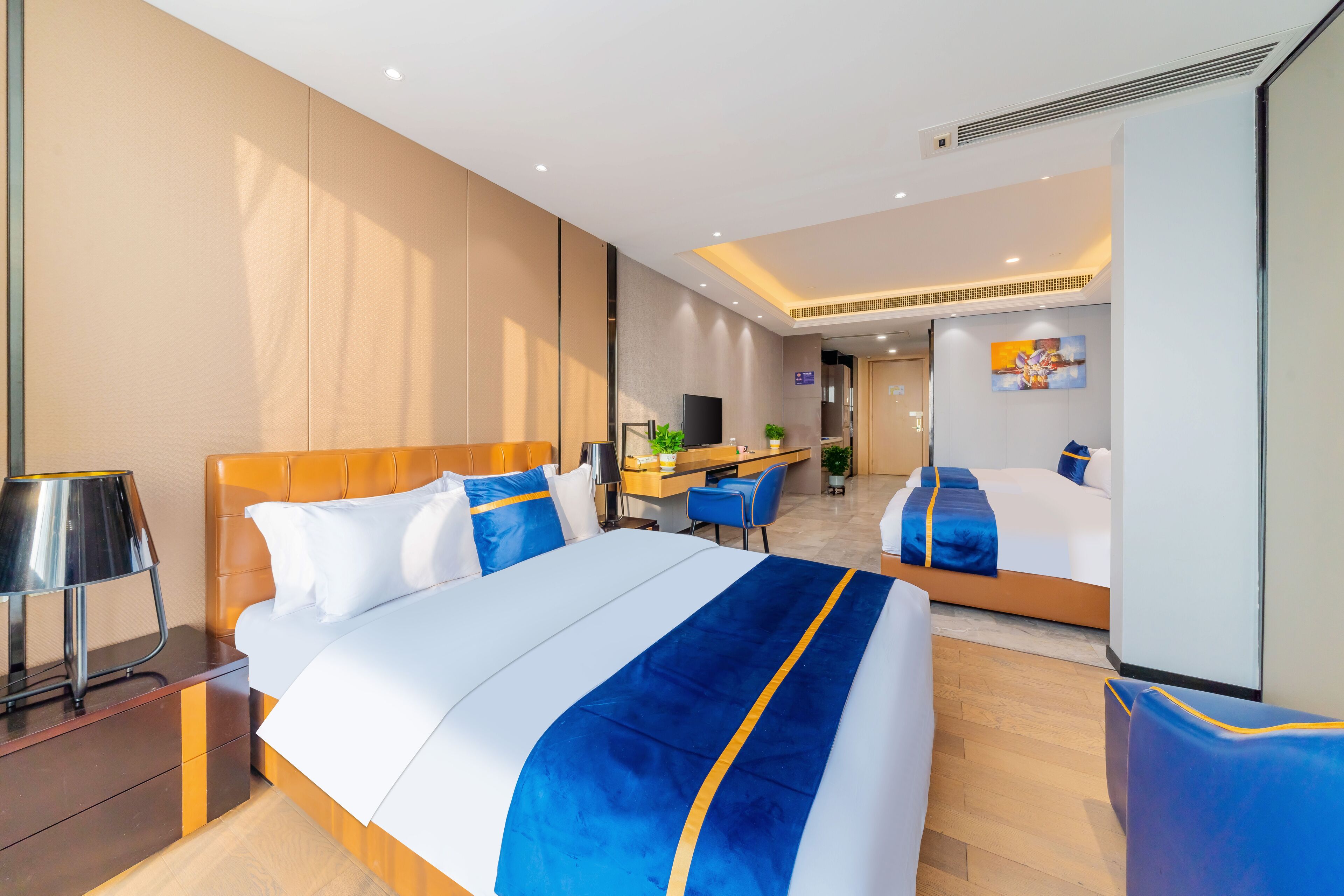 A hotel room with a large bed, a desk, a chair, and a TV.