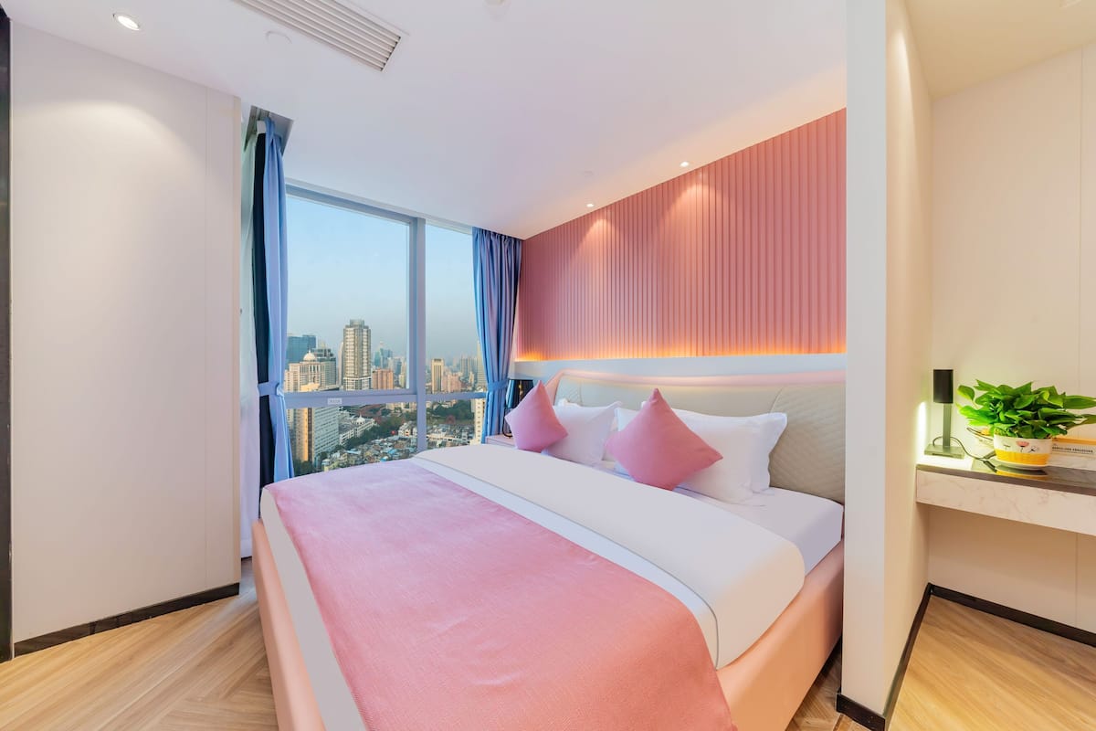 Quarto de hotel moderno com uma cama grande, uma escrivaninha e vista para a cidade.