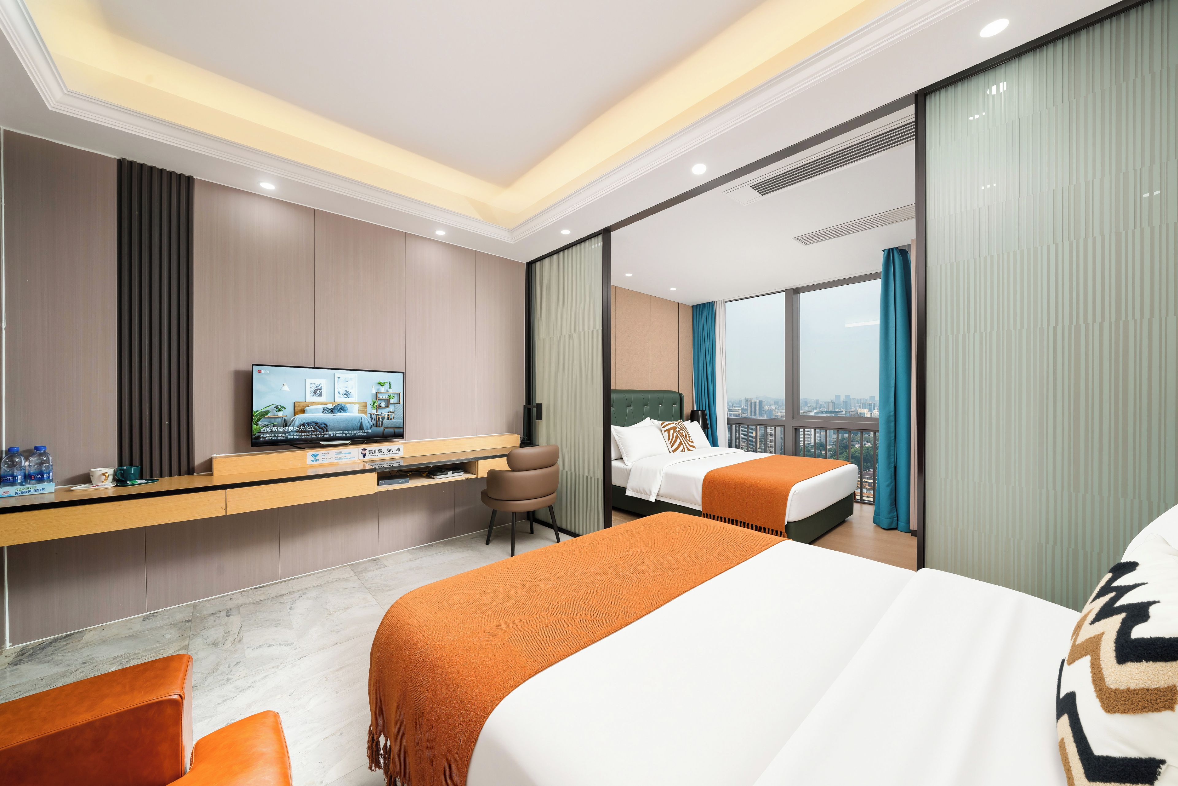 Una habitació d'hotel amb un llit, escriptori, televisió i vista a la ciutat.