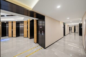 Un pasillo moderno de hotel con ascensores y una pantalla digital del plano de los pisos.