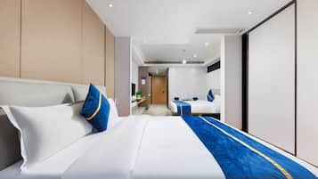 Une chambre d’hôtel moderne avec un grand lit, un bureau et une salle de bain que l’on aperçoit à l’arrière-plan.