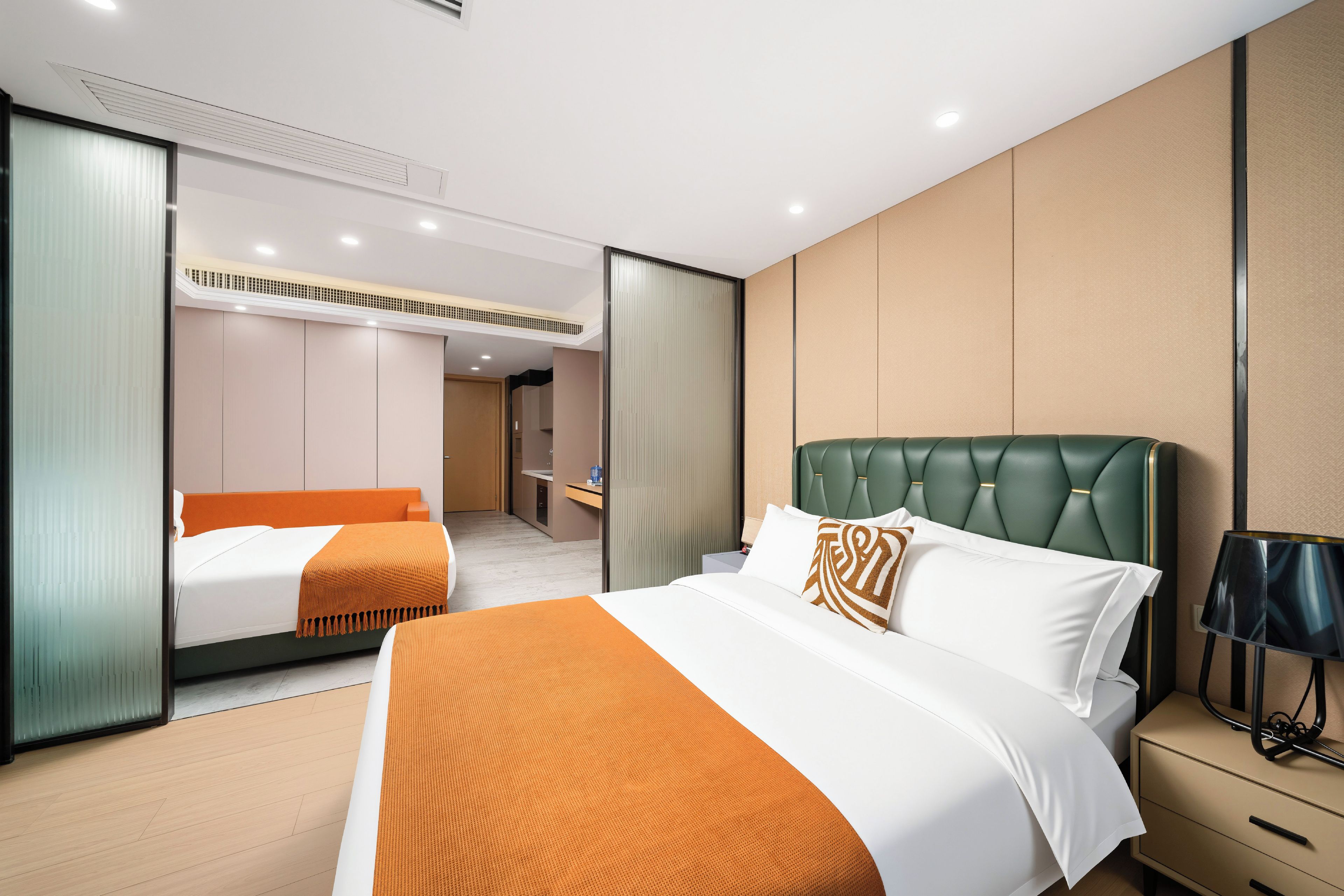Une chambre d’hôtel avec un grand lit, un lit plus petit, un bureau et un miroir.