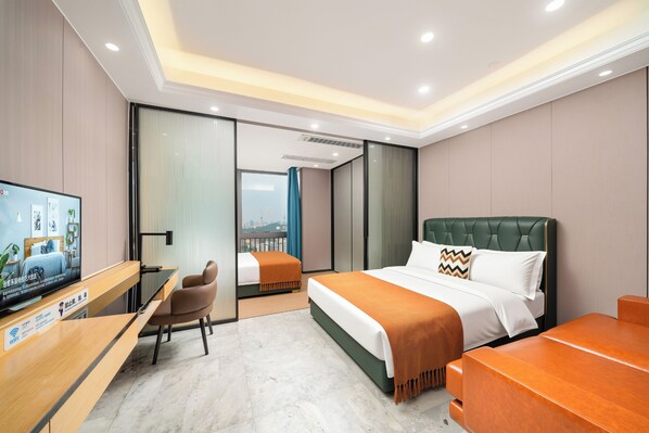 A hotel room with a bed, a desk, a chair, a television, and a view of the city.