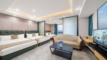 A hotel room with two beds, a sofa, a coffee table, and a TV.