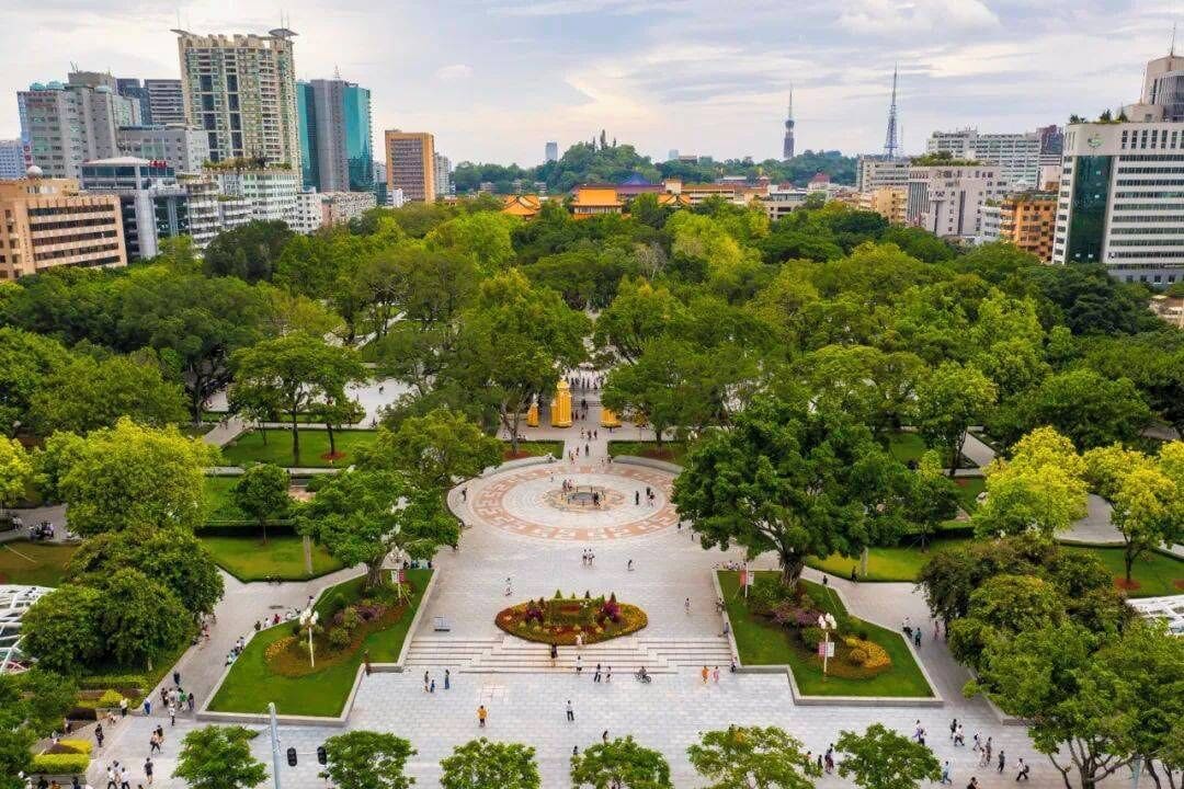 A large urban park with a central fountain, surrounded by trees and pathways.