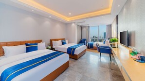 A hotel room with two beds, a desk, a chair, a TV, and a city view. - Cloudy International Apartment (Guangzhou)