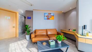 A modern lobby with a leather sofa, a coffee table, a desk, and a painting on the wall.